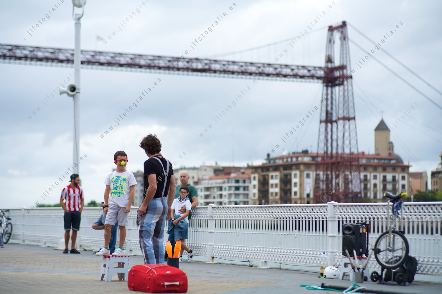 malabarista delante del puente colgante de Portugalete durante con un niño en la actuación