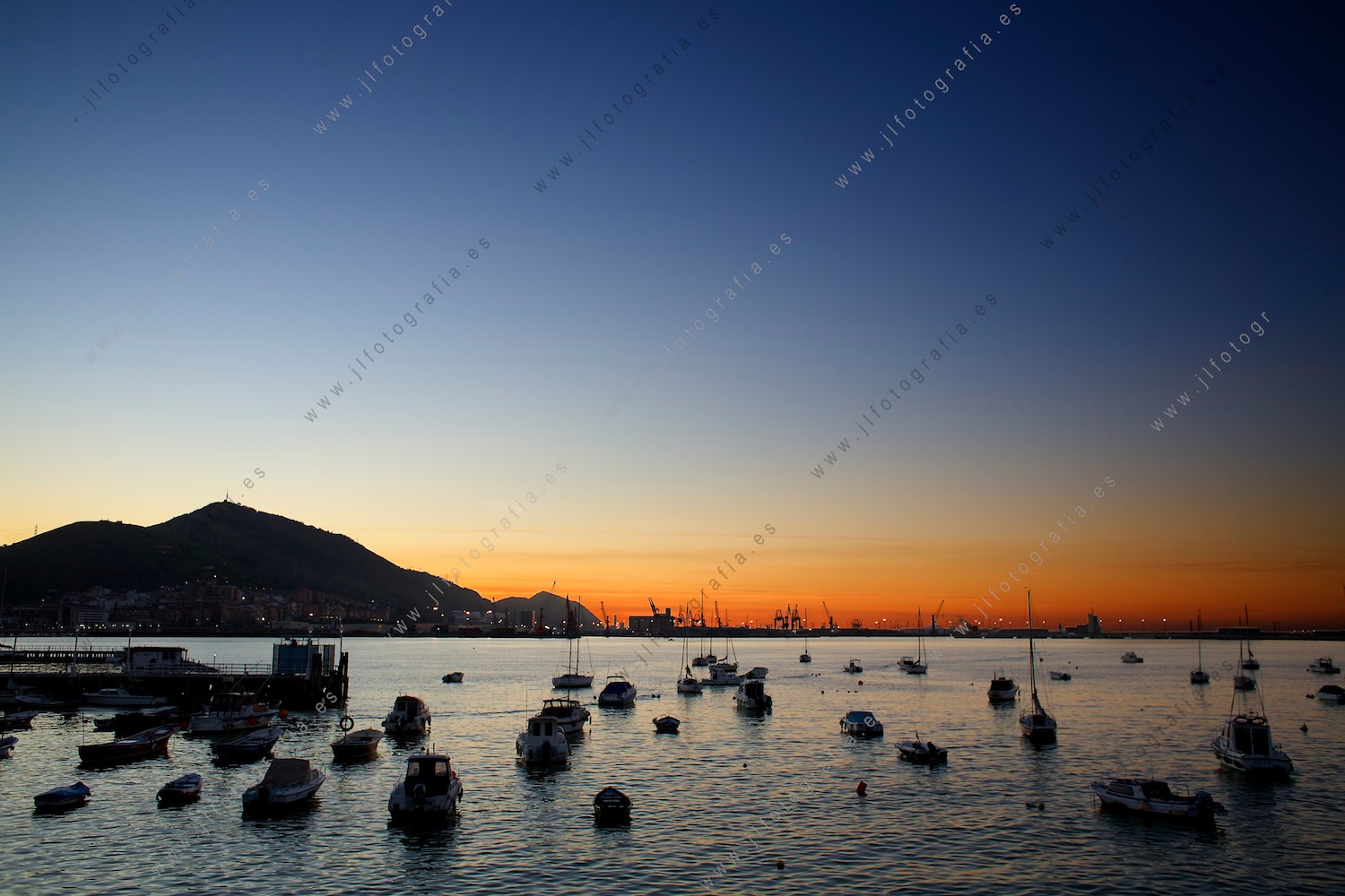 Ocaso desde el puerto deportivo de Getxo, con el monte Serantes y el superpuerto de Bilbao.