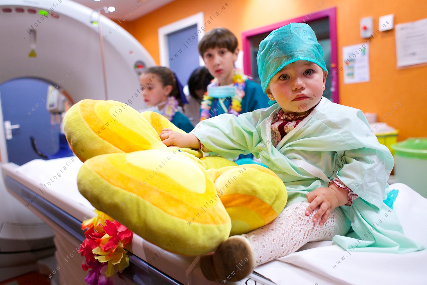 retrato de una niña sentada en la mesa de escáner del hospital de San Eloy durante de la sesión fotográfica del calendario solidario por la enfermedad de Sanfilippo
