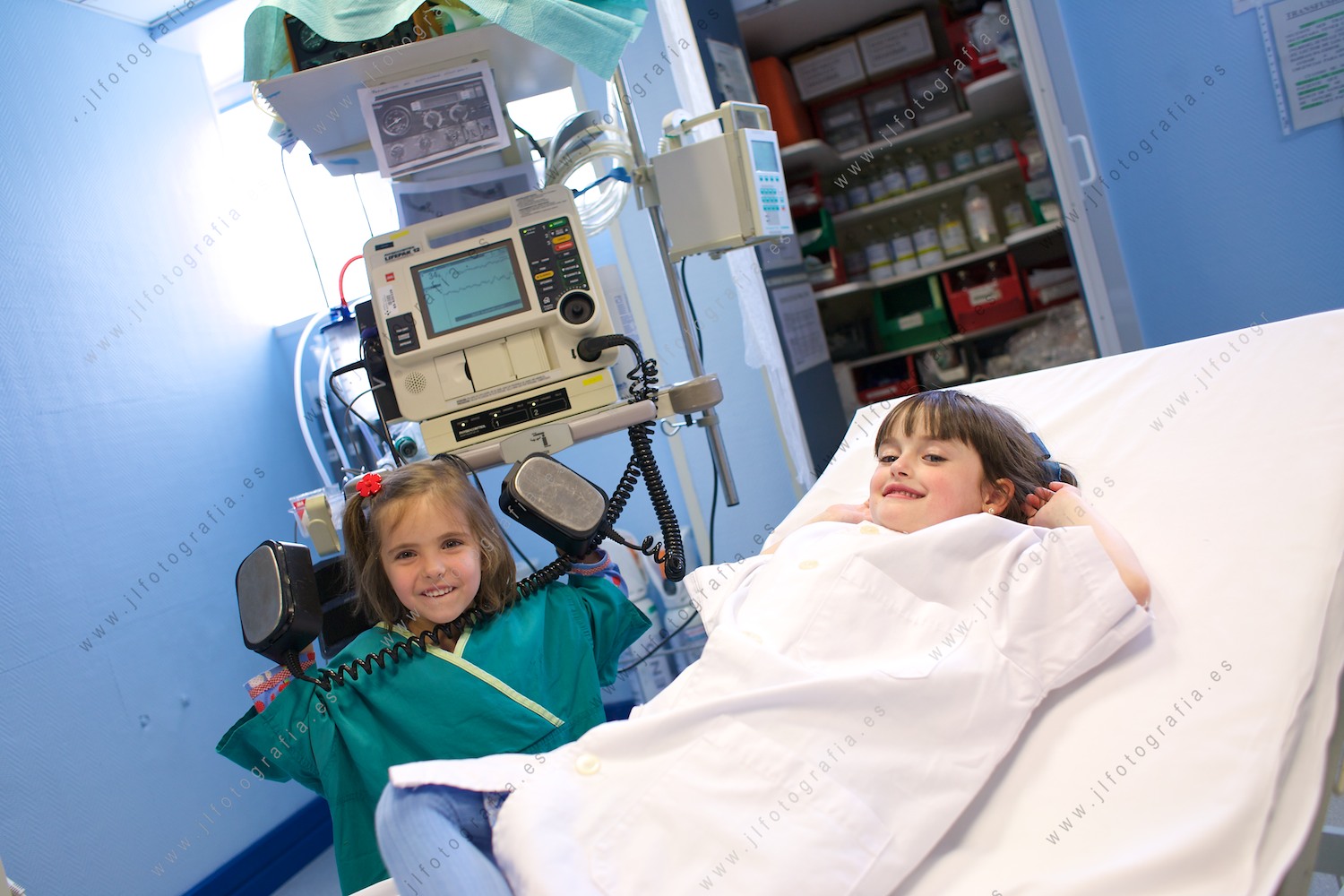 Dos niñas vestidas de médicos, con un desfibrilador de reanimación, posando en la sesión de retrato del calendario solidario por la enfermedad de Sanfilippo