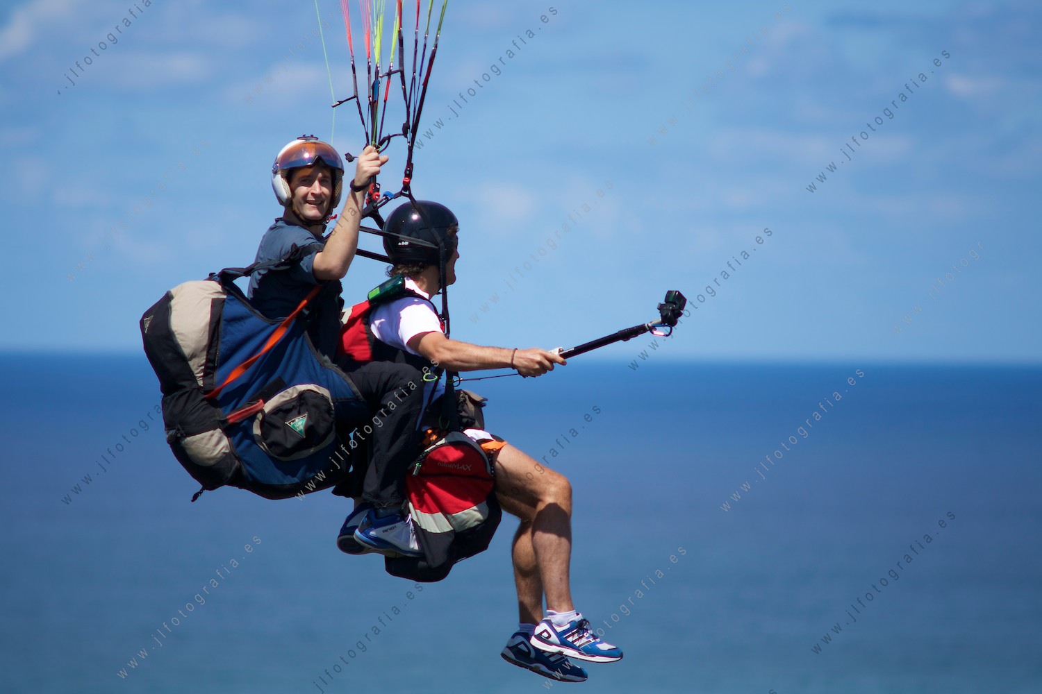 Dos parapentistas , retrato de plano completo, mirando a cámara mientras disfrutan por el aire
