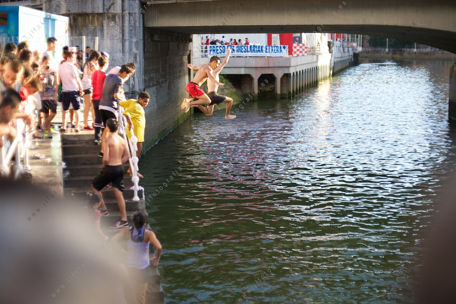 Aste Nagusia de Bilbao, dos jóvenes saltando desde la orilla al agua de la ría.