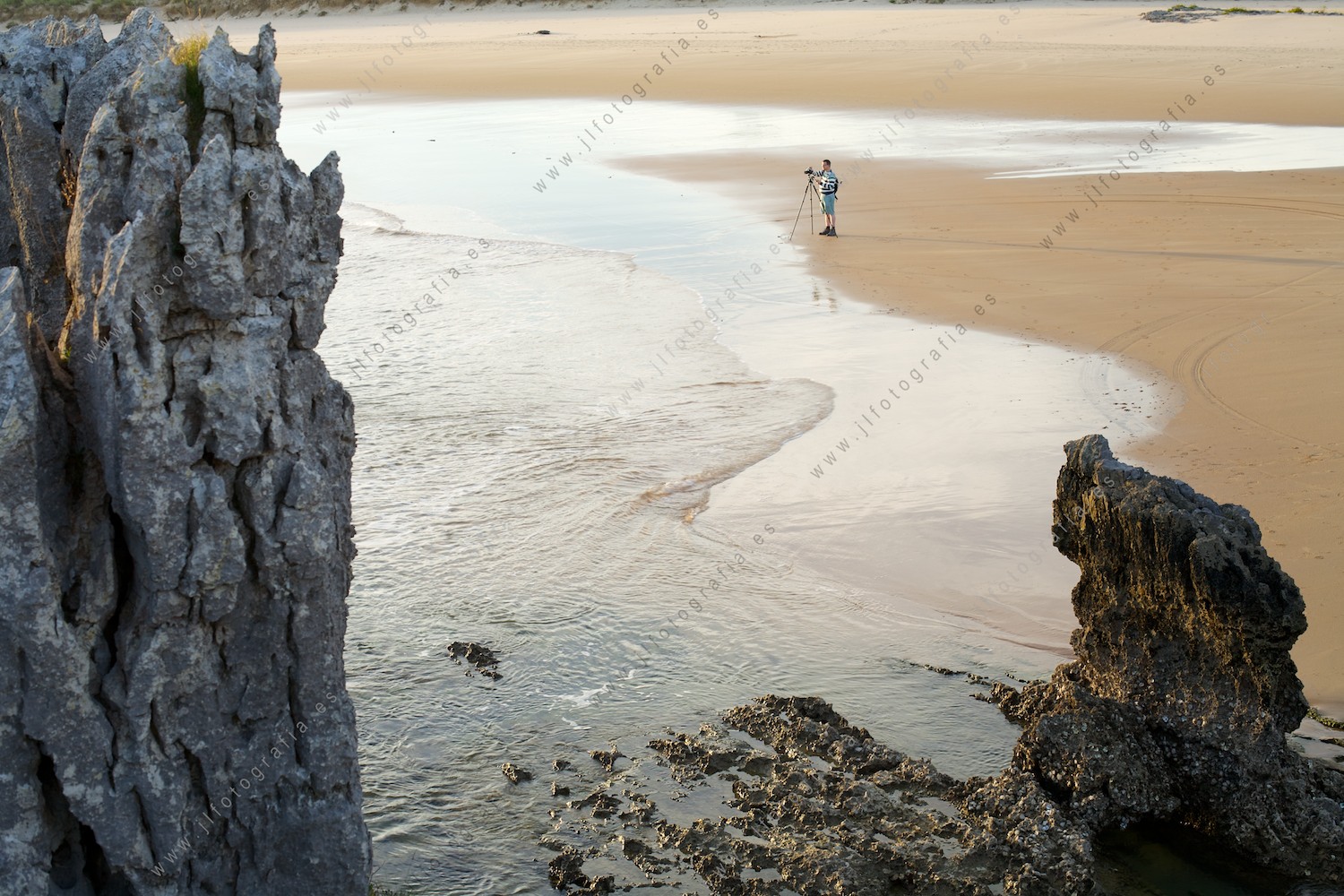 Fotógrafo en la playa de ris en Noja, desde la costa.