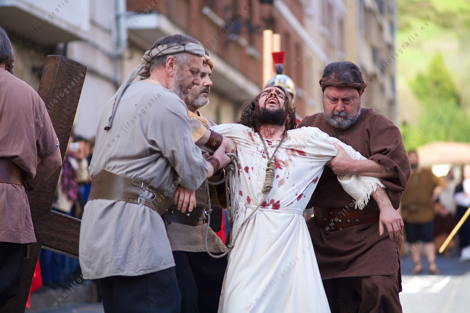 Ayudan a levantarse a cristo tras la segunda caida en el viacrucis de Balmaseda