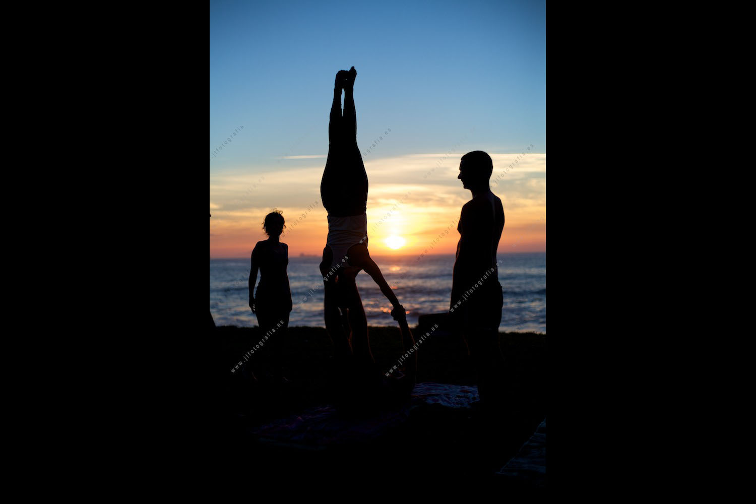 Siluetas de jóvenes practicando acroyoga durante el ocaso