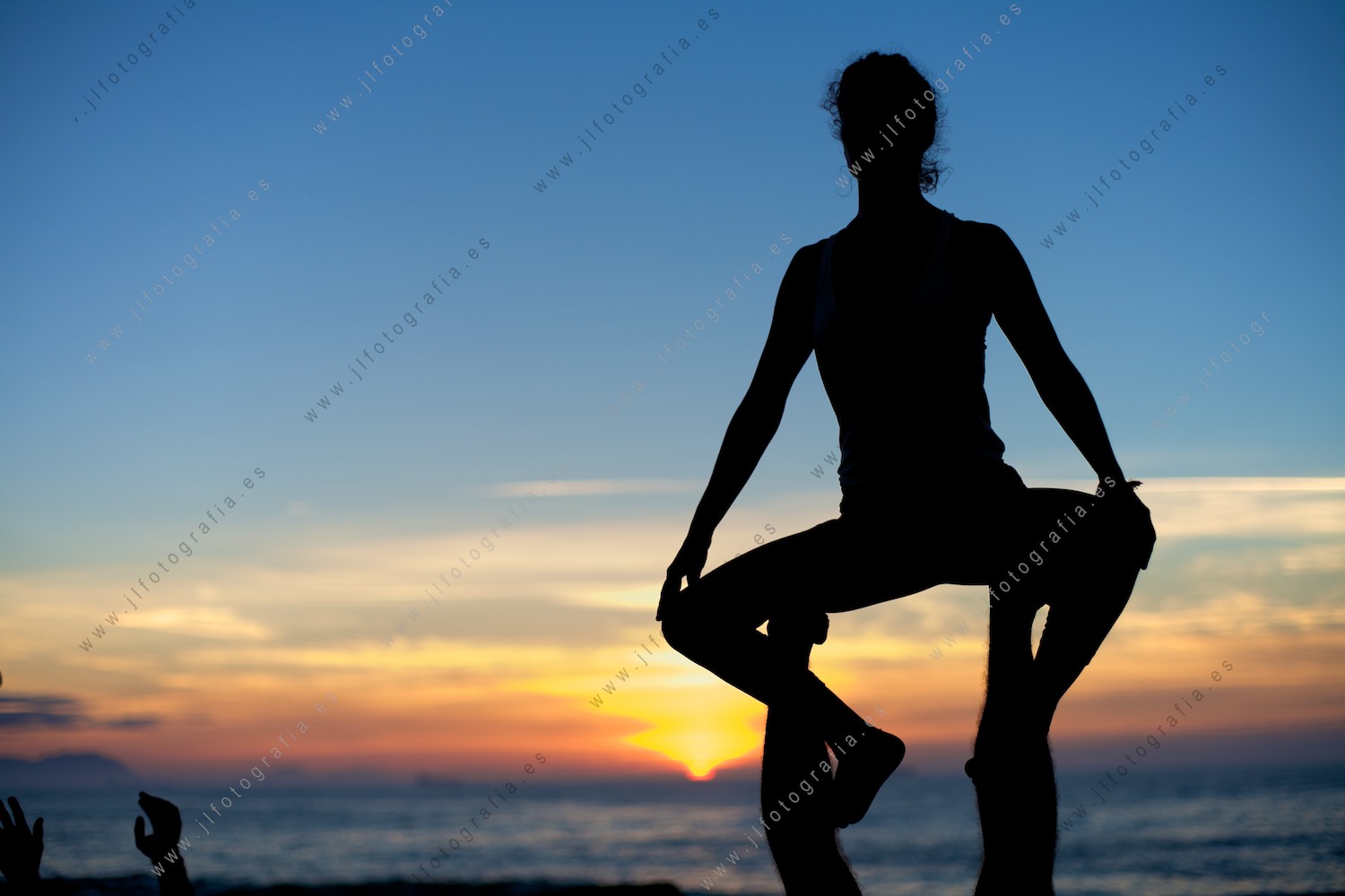Detalle de una chica practicando acroyoga en las últimas horas del día