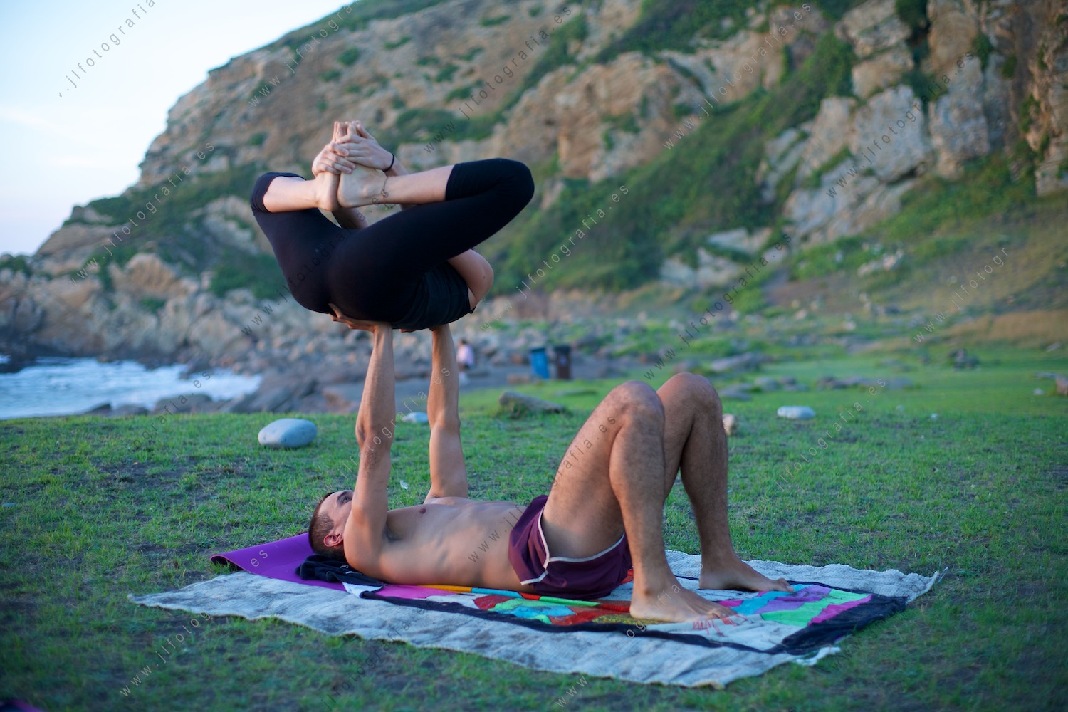 una pareja de jóvenes practicando acroyoga en Azkorri al atardecer