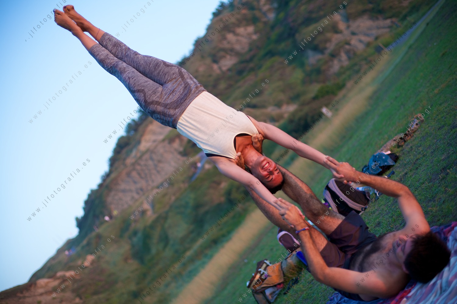 practicando una de las posiciones de ejercicio de acroyoga en Azkorri al atardecer