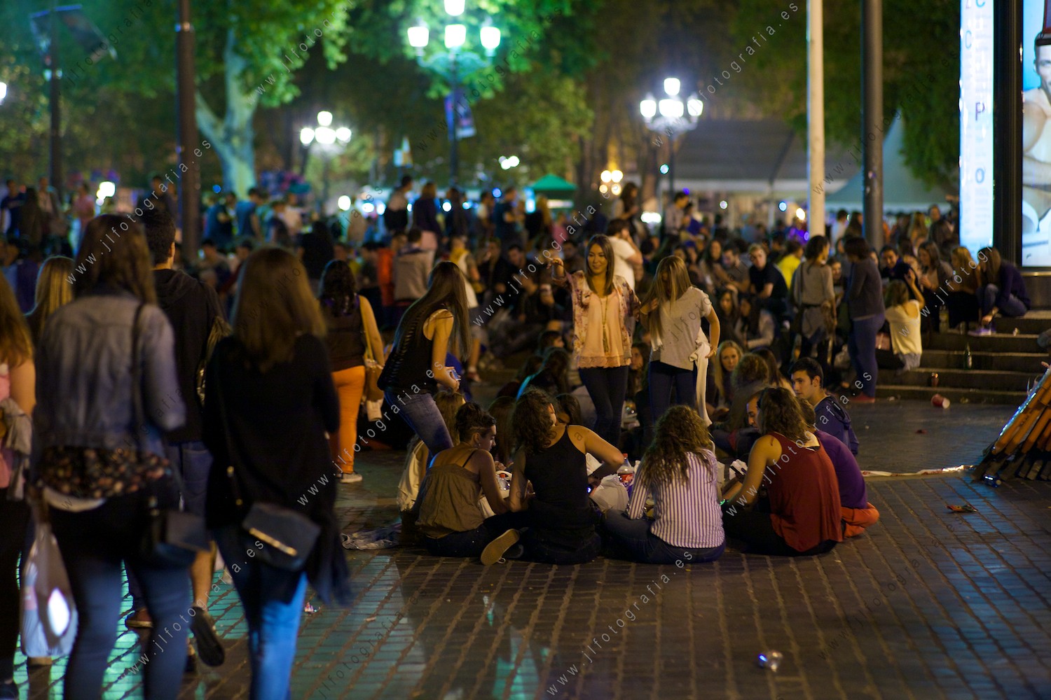 la gente joven forma corros donde sentarse y beber en la plaza del teatro Arriaga en fiestas de Bilbao