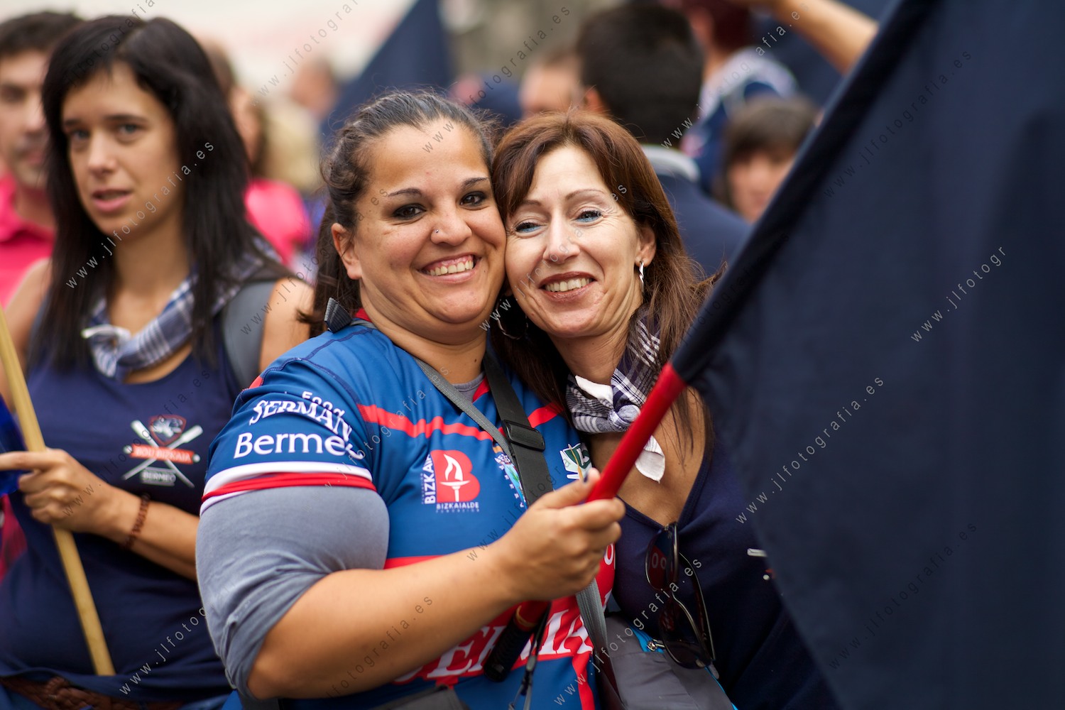 Dos aficionadas seguidoras de Urdaibai, con una bandera, me sorien para que les haga un retrato en el embarcadero de Donostia