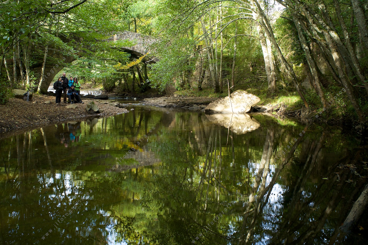 fotógrafos socios de Denbora, posando junto al puente en el río del parque natural del Gorbea en gran plano general.