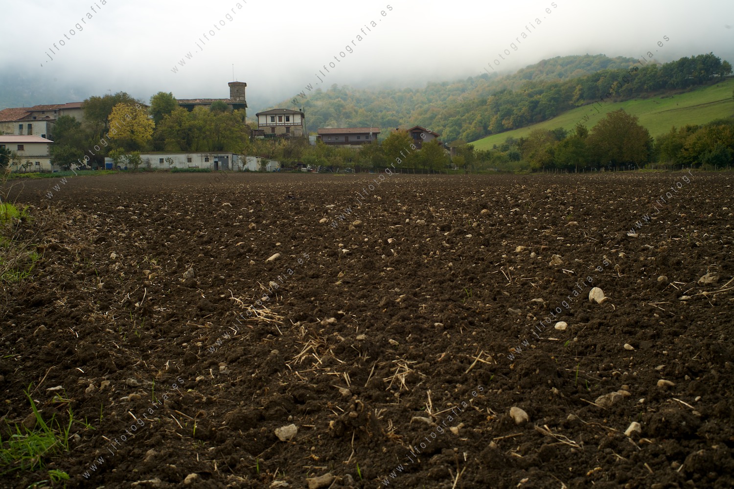 El pueblo de Andoin, Araba, emerge de los campos sembrados de patata delante de las nieblas de la sierra de Urbasa