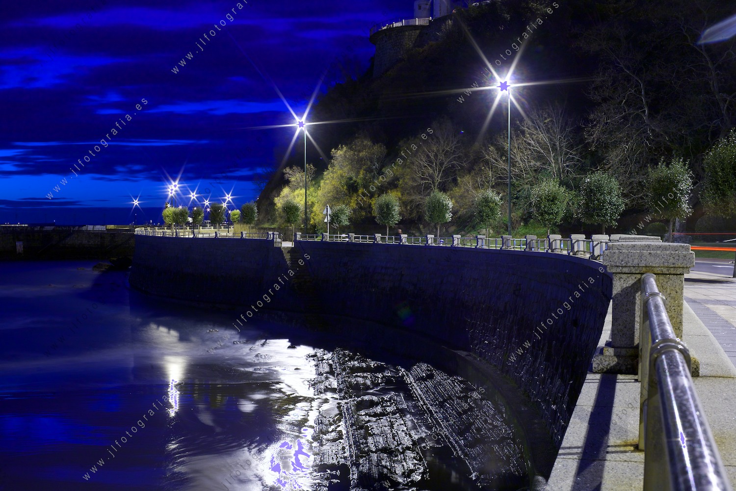 Paseo de la playa de Algorta hacia el puerto viejo, en Getxo, en la hora azul, con un balance de blancos extremo. 