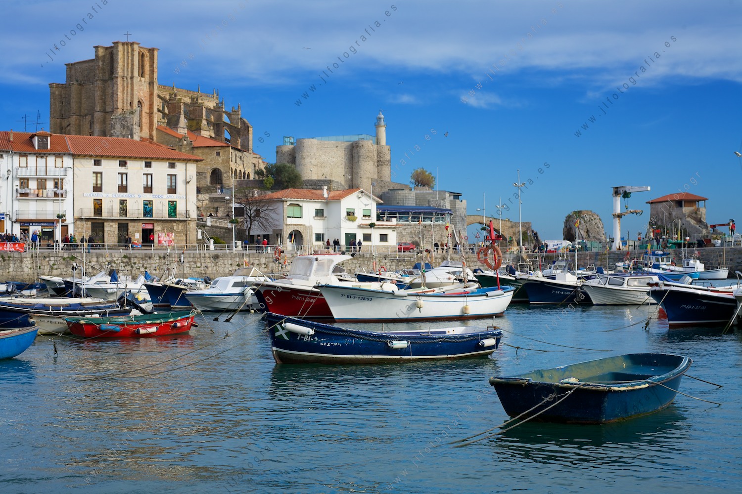 Puestro pesquero de Castro Urdiales con la Iglesia de Santa María y el faro de fondo.