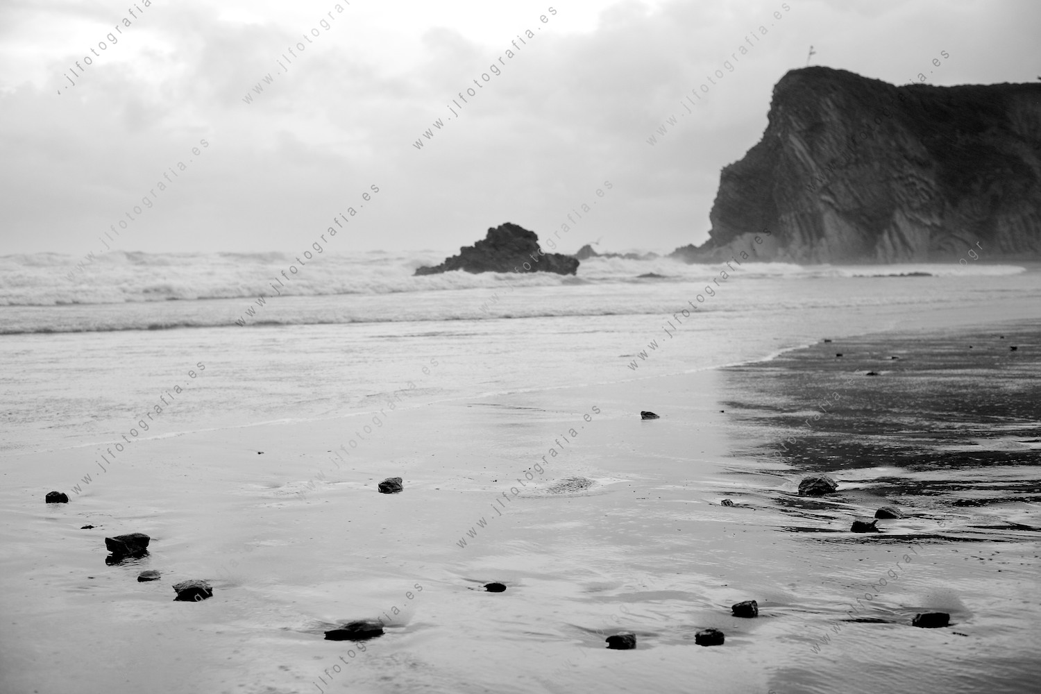 Encudre fotográfico del mar embravecido, mientras unas simples piedritas le retan a llevarlas al fondo del mar.
