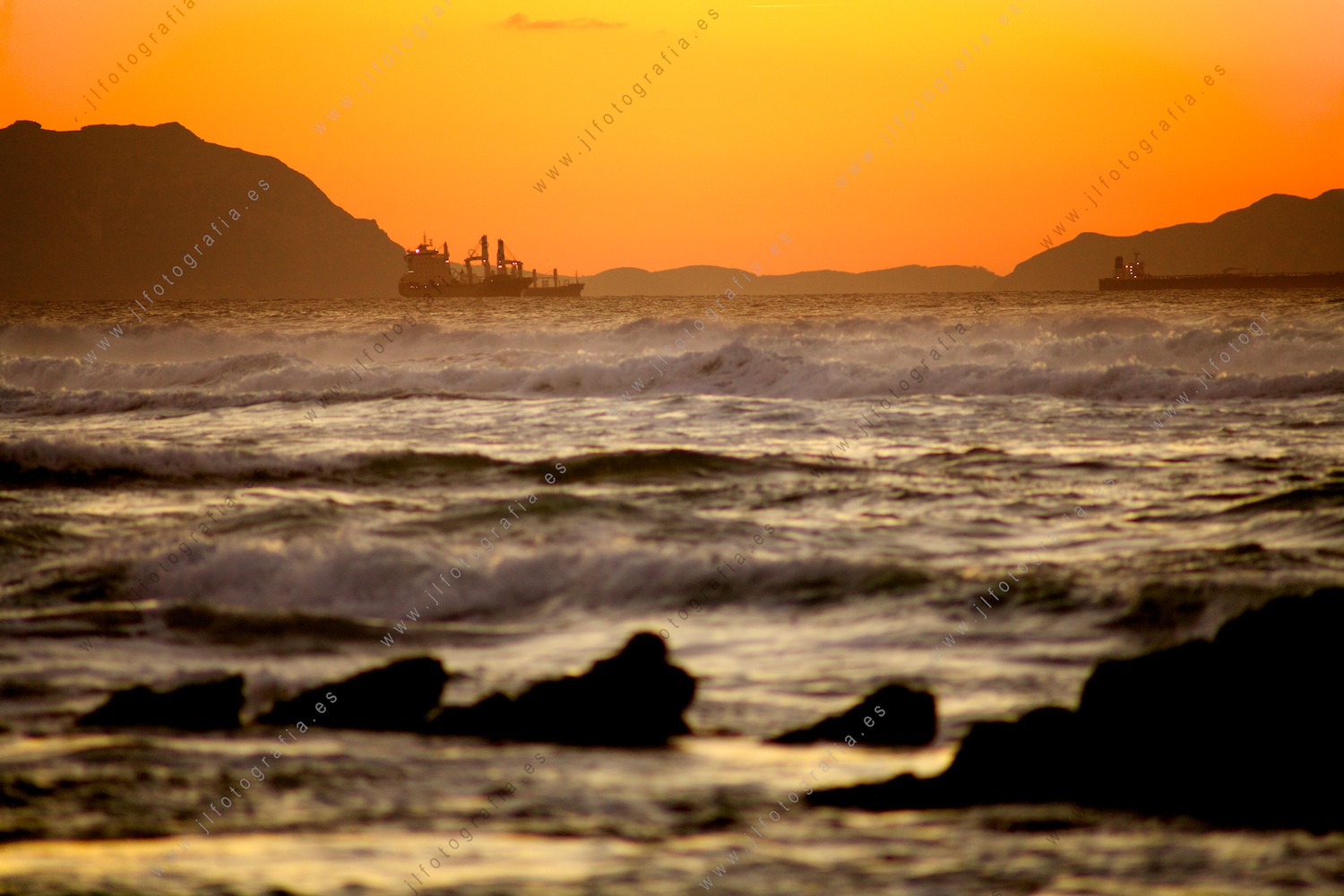 Varios barcos cargueros esperando cerca del puerto en el atardecer.