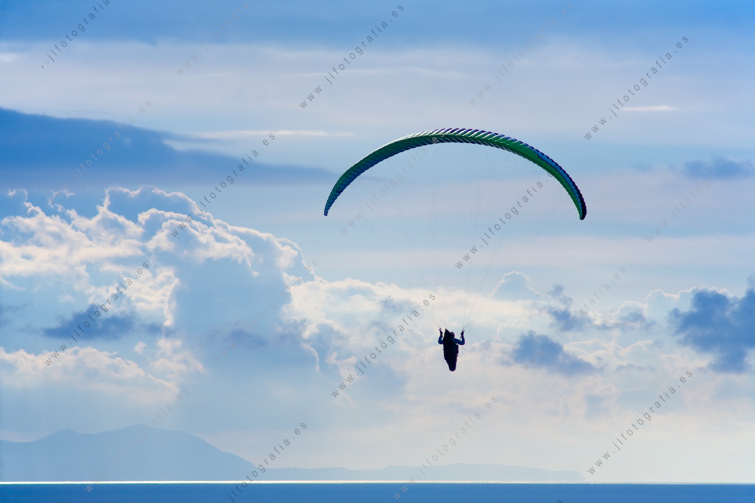 Un parapente vuela por el cielo azul calmado mar de nubes.